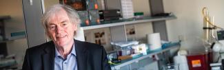 Dr. Pieter Cullis standing in front of shelves in his lab