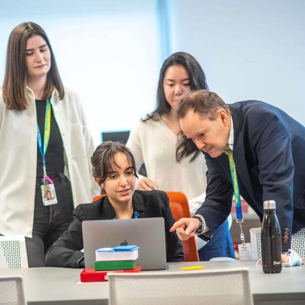 Dr. David Huntsman  with members of his research team huddled around a laptop