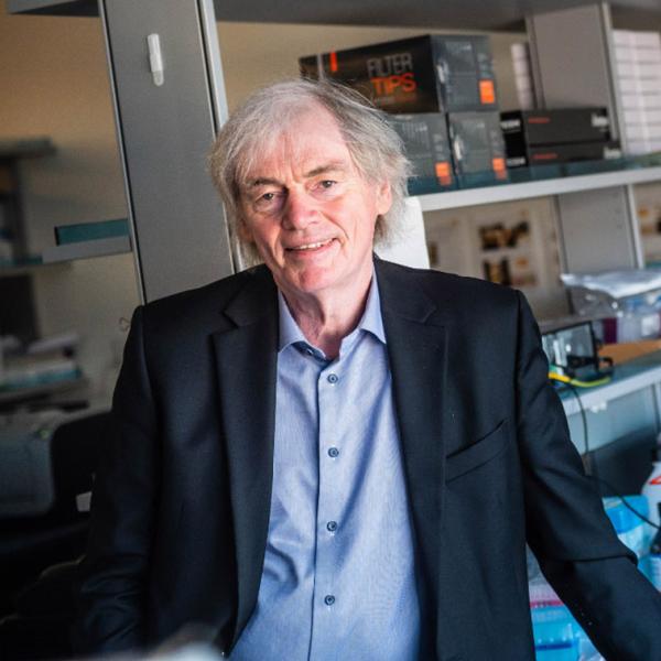 Dr. Pieter Cullis standing in front of shelves in his lab