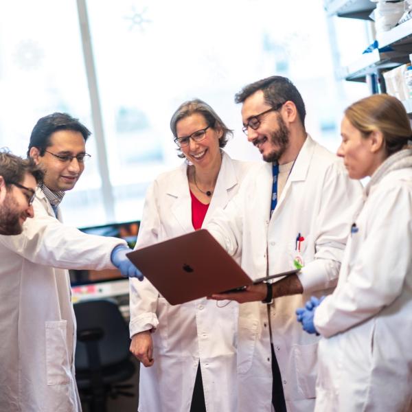 Dr. Megan Levings and her team looking at a laptop in a lab