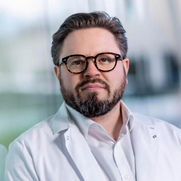 Dr. Shane Dugaan standing against a glass wall