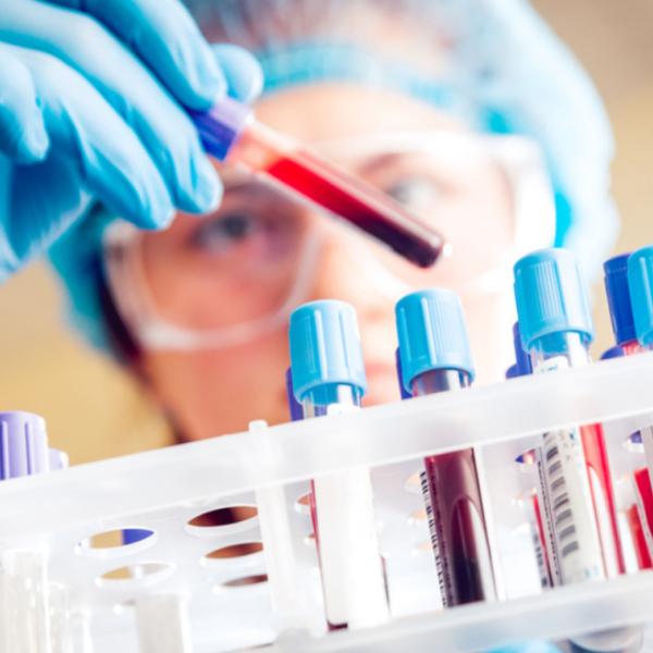 person looking at test tube of blood